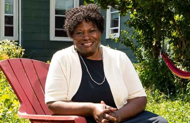 Participant Cynthia - person with dark curly hair sitting in a red chair and smiling