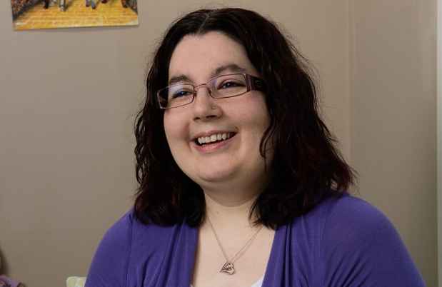 Participant Christina - person with shoulder length dark hair and glasses wearing a purple sweater