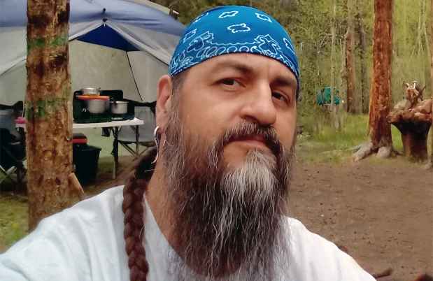 Deconstructing Stigma participant Ray - person poses in front of campsite in the woods