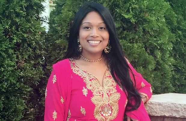 Participant Subrina - person with long dark hair wearing bright pink clothes and smiling in front of greenery