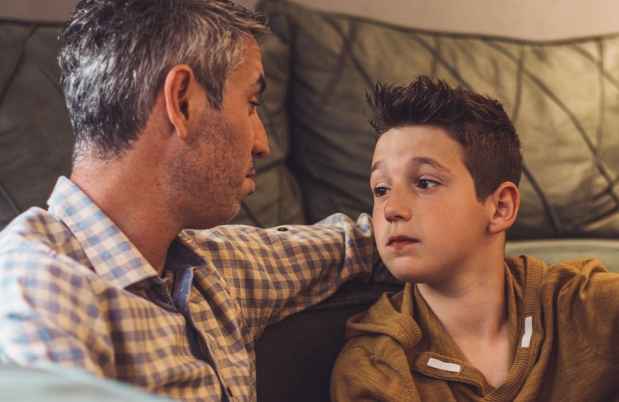 Man and boy sitting on the floor in front of a couch