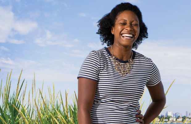 Deconstructing Stigma participant Ivy - person in black and white striped dress laughs outside on beach, sky in the background