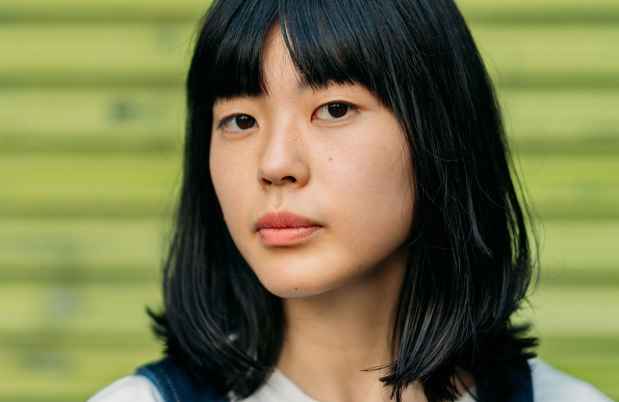 Young person looks out, green background