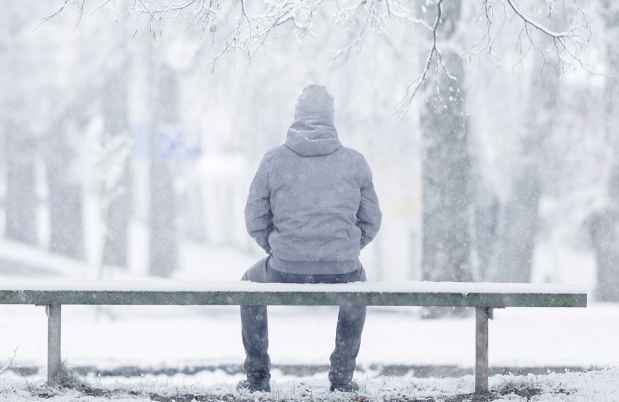 Figure sits on bench on snowy day