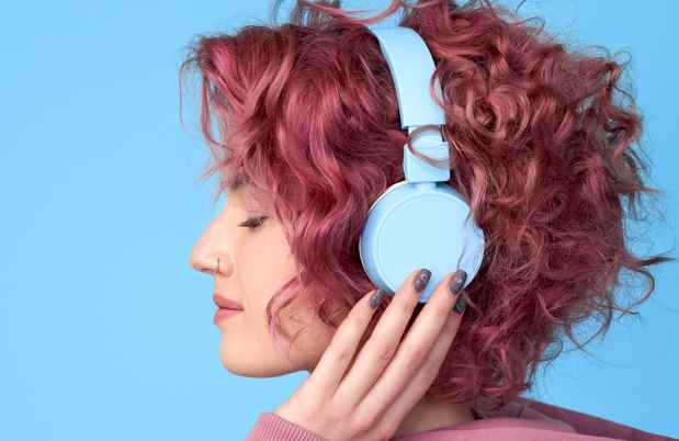 Young woman with pink hair wearing headphones