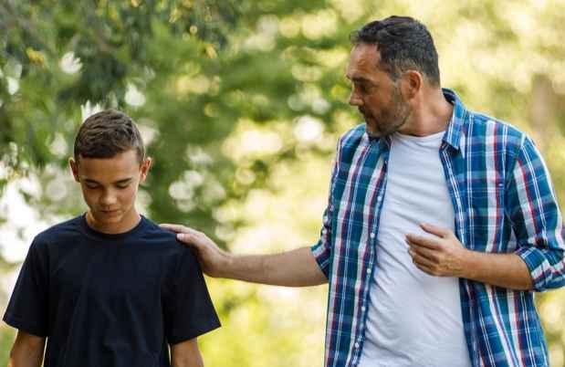 Dad and teen walk and talk outside