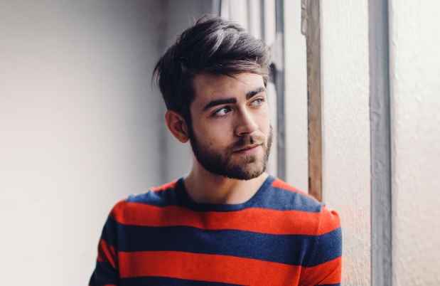 Young man in striped sweater looks out window