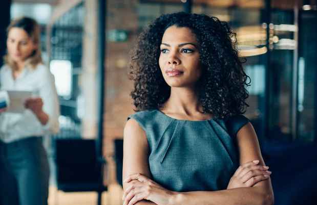 Woman in office stands away from a group of colleagues
