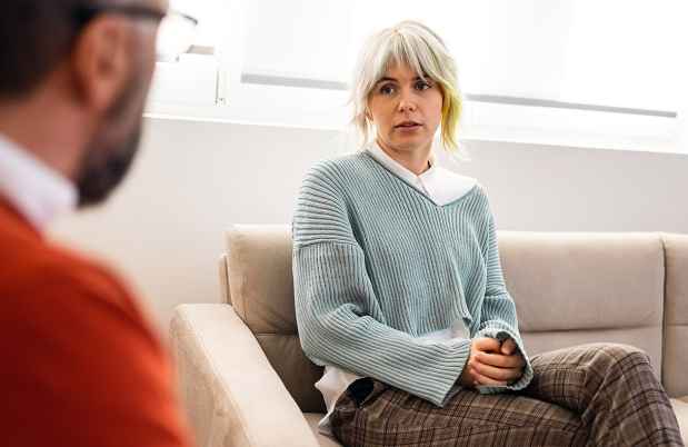 blonde woman seated, talking to a therapist