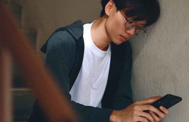 Teen sitting on stairs looking at his phone