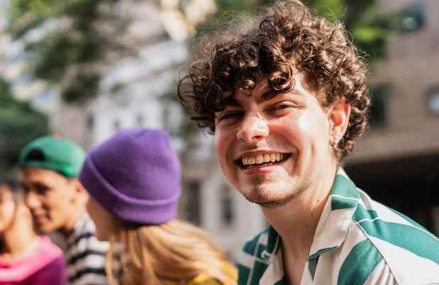 Person with short curly hair smiling