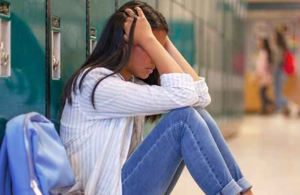 Girl sits against school lockers
