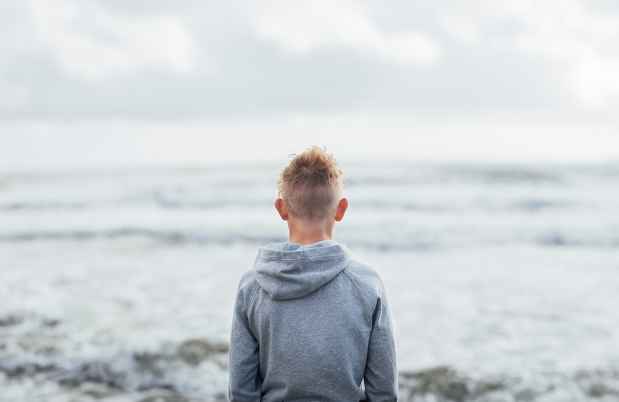 young boy staring out into the ocean