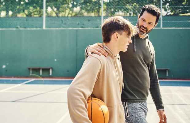 Man and boy walk together on outdoor basketball court