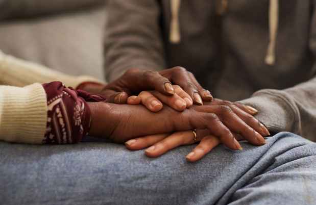 Close-up photo of hands held over one another in a comforting way