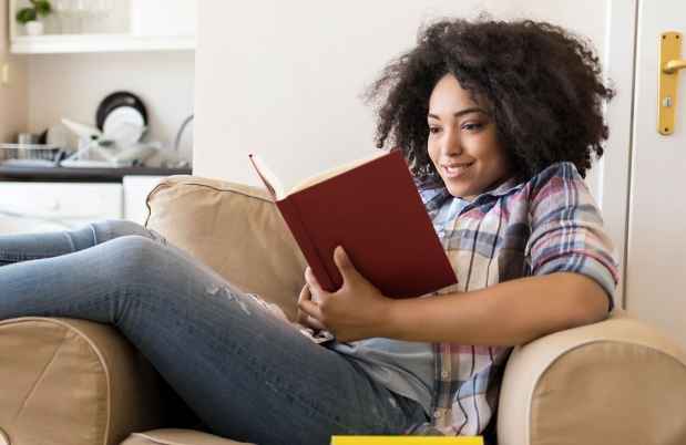 woman sitting in lounge chair reading a book