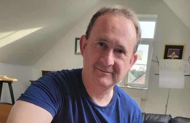 Deconstructing Stigma participant Paul - person sits on couch playing guitar