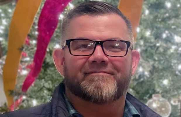 Deconstructing Stigma participant Tom - person with glasses in front of indoor decorated tree