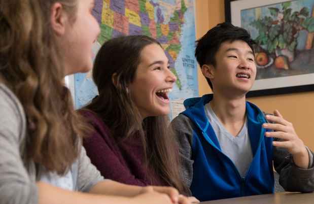 Group of adolescents laughing together at a table