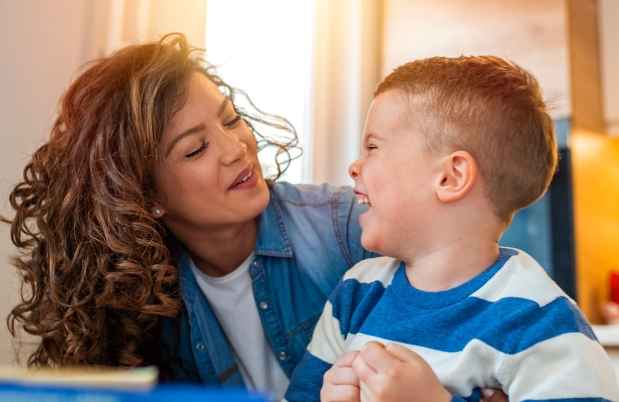 Caregiver and young child laugh together