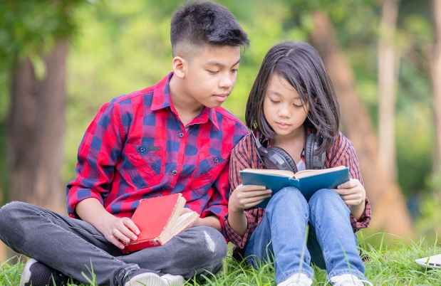 Teen and kid reading outside