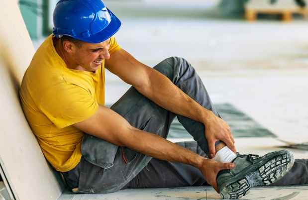 Construction worker in hard hat holds leg in pain