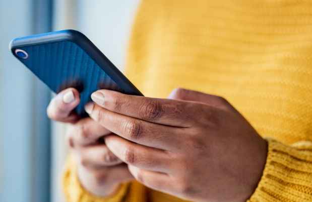 Hands holding smartphone, person wears bright yellow sweater