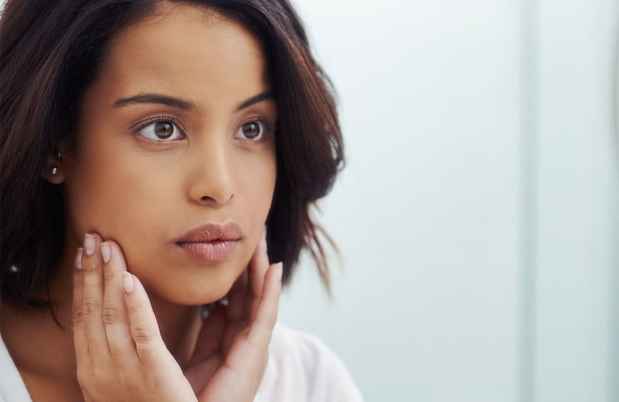 Person looking in mirror, hands on face