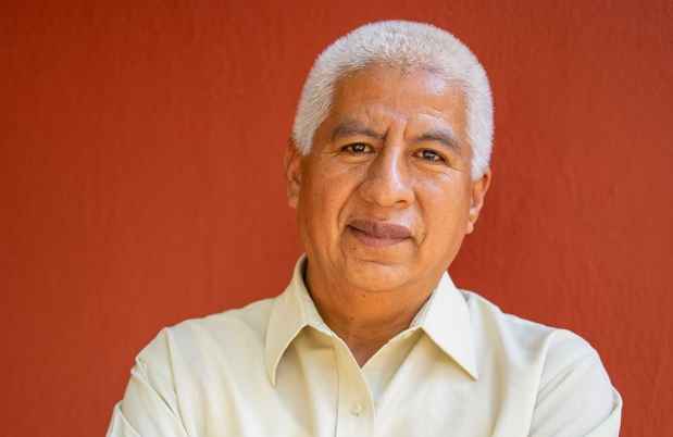 Stock image of an older adult in white button down in front of red wall