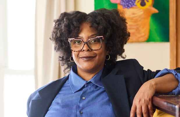 Deconstructing Stigma participant Johanne - person in blue blazer stands by bookcase