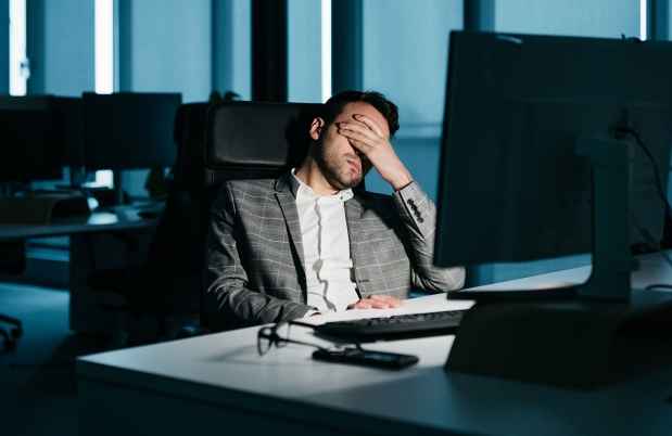 Person in darkened office slumped in front of computer
