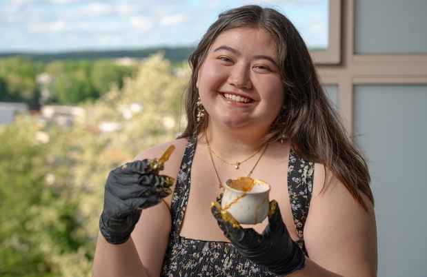 Deconstructing Stigma participant Natalie - young person holds broken cup and stick with gold paint to fix