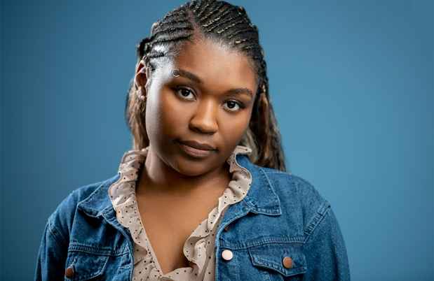 Deconstructing Stigma participant Jamorra - person with long braids poses on blue background
