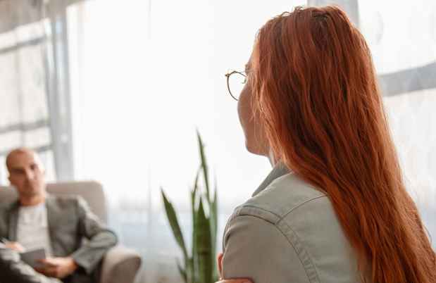 Woman with red hair sitting in front of window and therapist