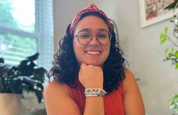 Deconstructing Stigma participant Lisa - young person in glasses and bandana sits with head perched on hand