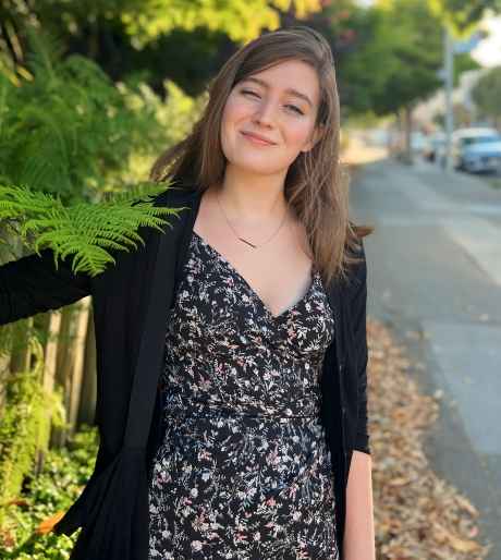 Participant Kellie - person in patterned dress smiling in front of greenery