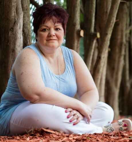 Participant Lisa - person with short hair sitting among autumnal leaves and trees