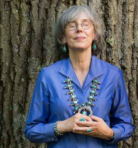 Participant Luanna - person with short grey hair leaning against a big tree trunk