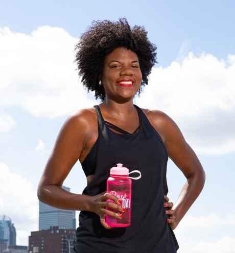 Participant Nieisha - person with dark curly hair smiling in front of the Boston skyline