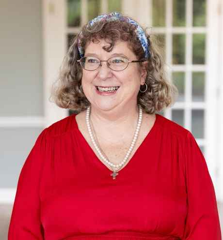Participant Mary - person with wavy grey hair smiling and wearing a bright red dress