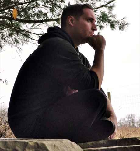 Participant Brian sits cross legged with hand underneath chin