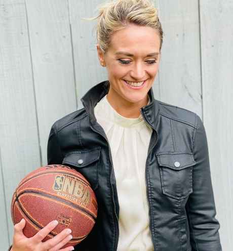 Participant Mandy - person with blond hair pulled back into an updo wearing a black leather jacket and holding a basketball