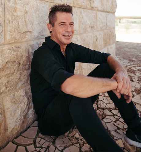 Deconstructing Stigma participant Omri - person sitting on ground leaning against stone wall