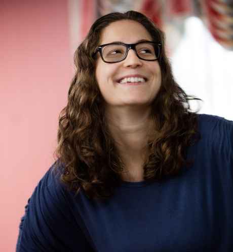 Participant Meredith - person with wavy brown hair and glasses smiling in front of a window