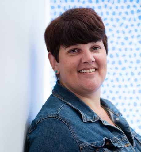 Participant Jennifer - person with short dark hair smiling in front of a blue and white wall
