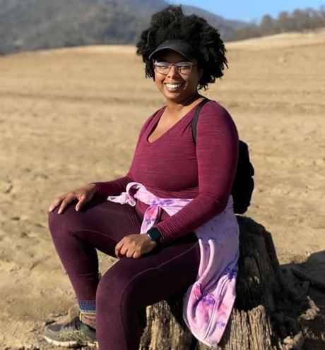 Participant Chezia sitting on a stump