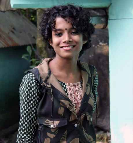 Deconstructing Stigma participant Sampurna - person with curly dark hair poses for camera