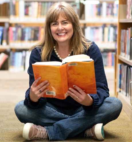 Deconstructing Stigma participant Martha - person sits on library floor holding a book