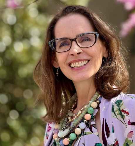 Deconstructing Stigma participant Holly - person with distinctive glasses and chunky necklace poses outside