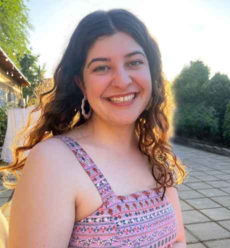 Deconstructing Stigma participant Kam - person with curly hair and multicolor dress on outdoor patio